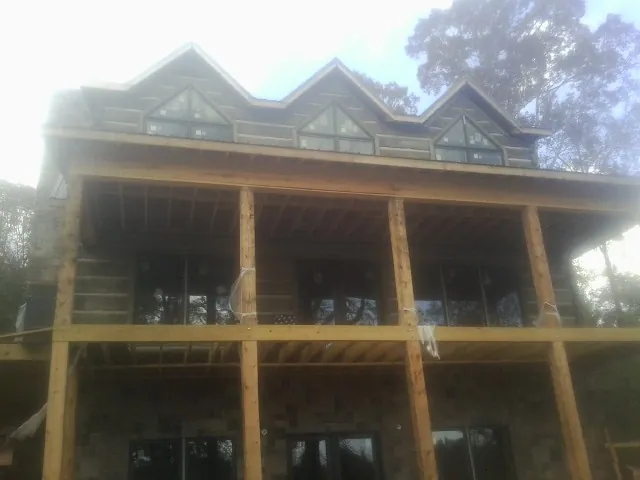 Dormers and porch framing on a large log home under construction — Roof Coating work by our crew in Dundee