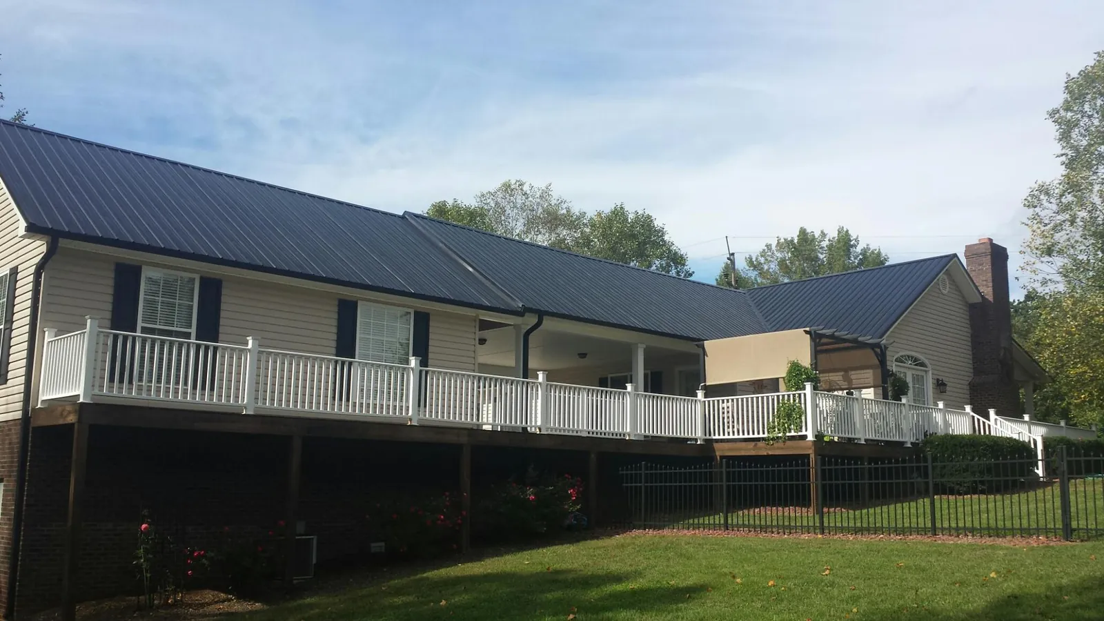 Black metal roof above a long white railed deck on a hillside home in Dundee